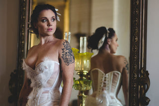 A fair model with freckles poses in a sheer and white panelled corset inspired by the Snowy Owl. The ensemble featured beadwork and feathers