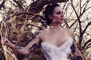 A fair model with freckles poses in a sheer and white panelled corset inspired by the Snowy Owl. The ensemble featured beadwork and feathers