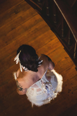 A fair model with freckles poses in a sheer and white panelled corset inspired by the Snowy Owl. The ensemble featured beadwork and feathers
