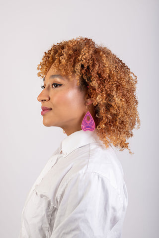 A woman in a white shirt wears the perfect planchette earrings in pink by The Bad button