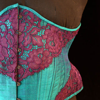A Bad Button bespoke corset design by Alisha Martin featuring an aqua fabric and pink lace detailing