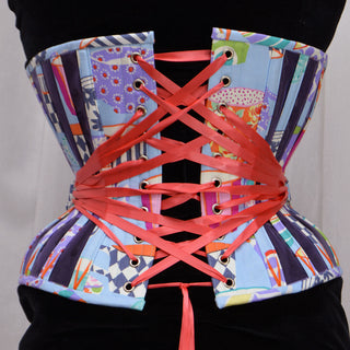 A Bad Button bespoke corset design by Alisha Martin featuring a colorful coffee cup fabric, blue panelling and bright pink lacing