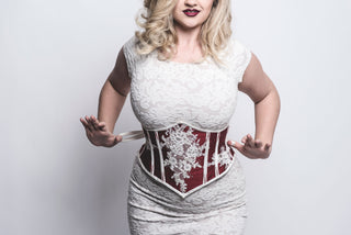 A Bad Button bespoke corset design by Alisha Martin featuring a red background and white lace detailing