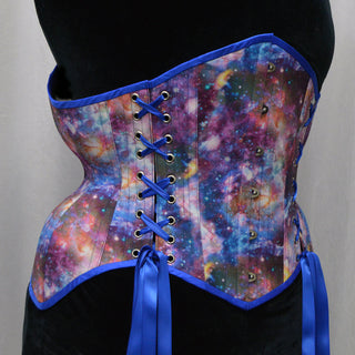 A Bad Button bespoke corset design by Alisha Martin featuring a galaxy print and bright blue lacing and detailing