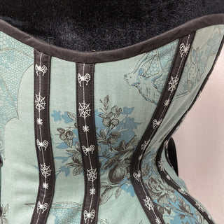 A Bad Button bespoke corset design by Alisha Martin featuring a pale green fabric covered in flowers and bats with black detailing
