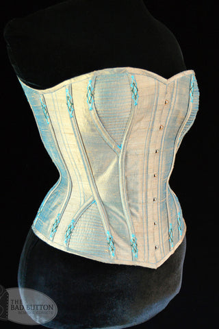 A Bad Button bespoke corset design by Alisha Martin featuring a pale blue fabric with bright blue stitching detail