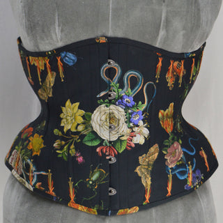 A Bad Button bespoke corset design by Alisha Martin featuring a black fabric covered in illustrations of flowers, snakes and insects