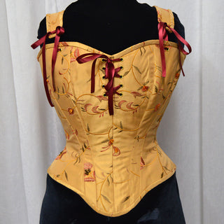 A Bad Button bespoke corset design by Alisha Martin featuring a yellow base with orange flower detailing and red lacing