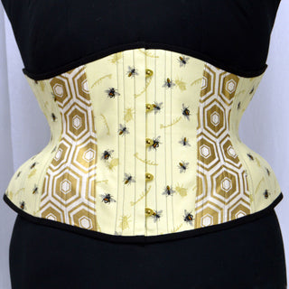 A Bad Button custom corset design by Alisha Martin featuring a pale yellow geometric print fabric covered in bee motifs