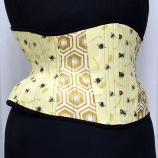 A Bad Button custom corset design by Alisha Martin featuring a pale yellow geometric print fabric covered in bee motifs