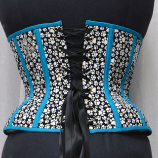 A Bad Button custom corset design by Alisha Martin featuring black and white pawprint fabric and bright blue piping