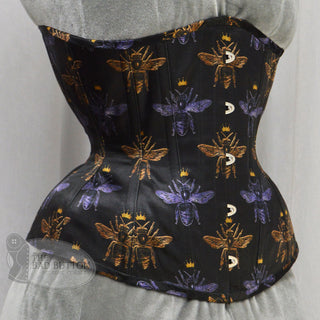 A Bad Button custom corset design by Alisha Martin featuring black fabric with gold and purple bees wearing crowns