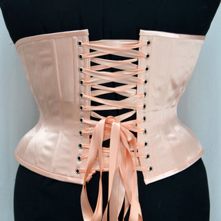 A Bad Button custom corset design by Alisha Martin in a delicate light pink color
