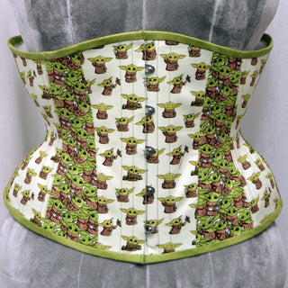 A Bad Button custom corset design by Alisha Martin featuring a white fabric with small baby yodas printed onto it