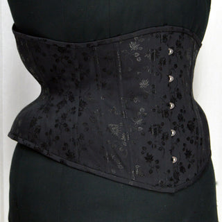 A Bad Button custom corset design by Alisha Martin featuring a black fabric with small satin flower detailing