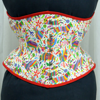 A Bad Button custom corset design by Alisha Martin featuring a white fabric with rainbow animals and confetti with red piping and yellow lacing
