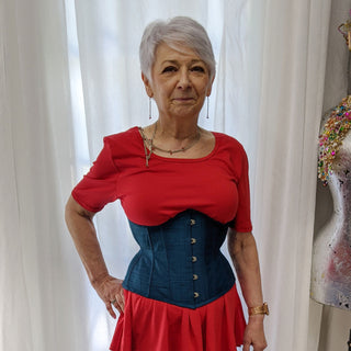 A The Bad Button bespoke corset design is being worn by an older woman in a red shirt and blue corset