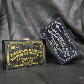 The Bad Button ouija board in gold and silver sits in a grey background