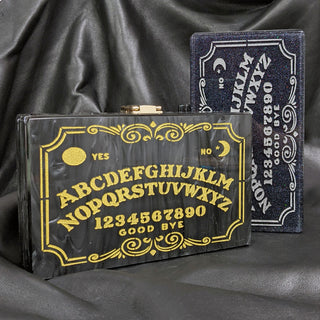 The Bad Button ouija board in gold and silver sits in a grey background