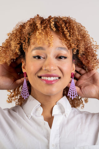 A woman with curly hair wears the Lydia Spiderweb earrings by The Bad Button