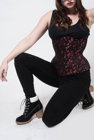 Red Rosebud Coutil black corset features delicate red floral detail. 